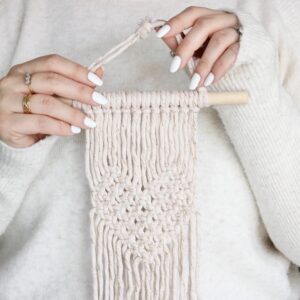 DIY Macramé Heart Tapestry Kit with eco-friendly packaging, 30 colour options, and included materials like wooden dowel, cotton cords, and S-hooks.
