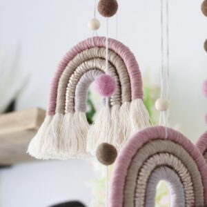 Piglet&Chestnut handmade rainbow macramé mobile with four macramé rainbows and cascading pompoms, hung from a wooden hoop