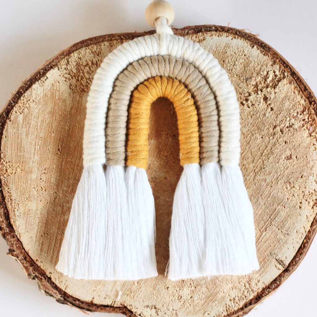 Handmade mini 3-arch macramé rainbow in soft, vibrant colours, displayed in a gift box.